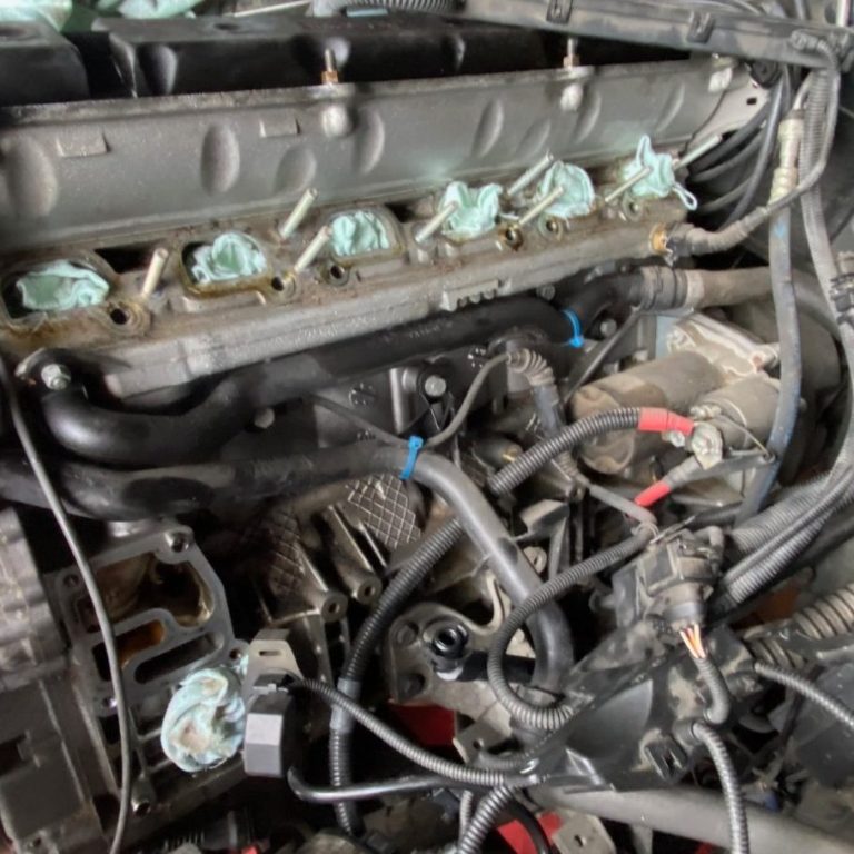 Der Reihen 6Zylinder im BMW Motorraum mit Zylinderkopf, Schläuchen und abgedeckten Öffnungen.